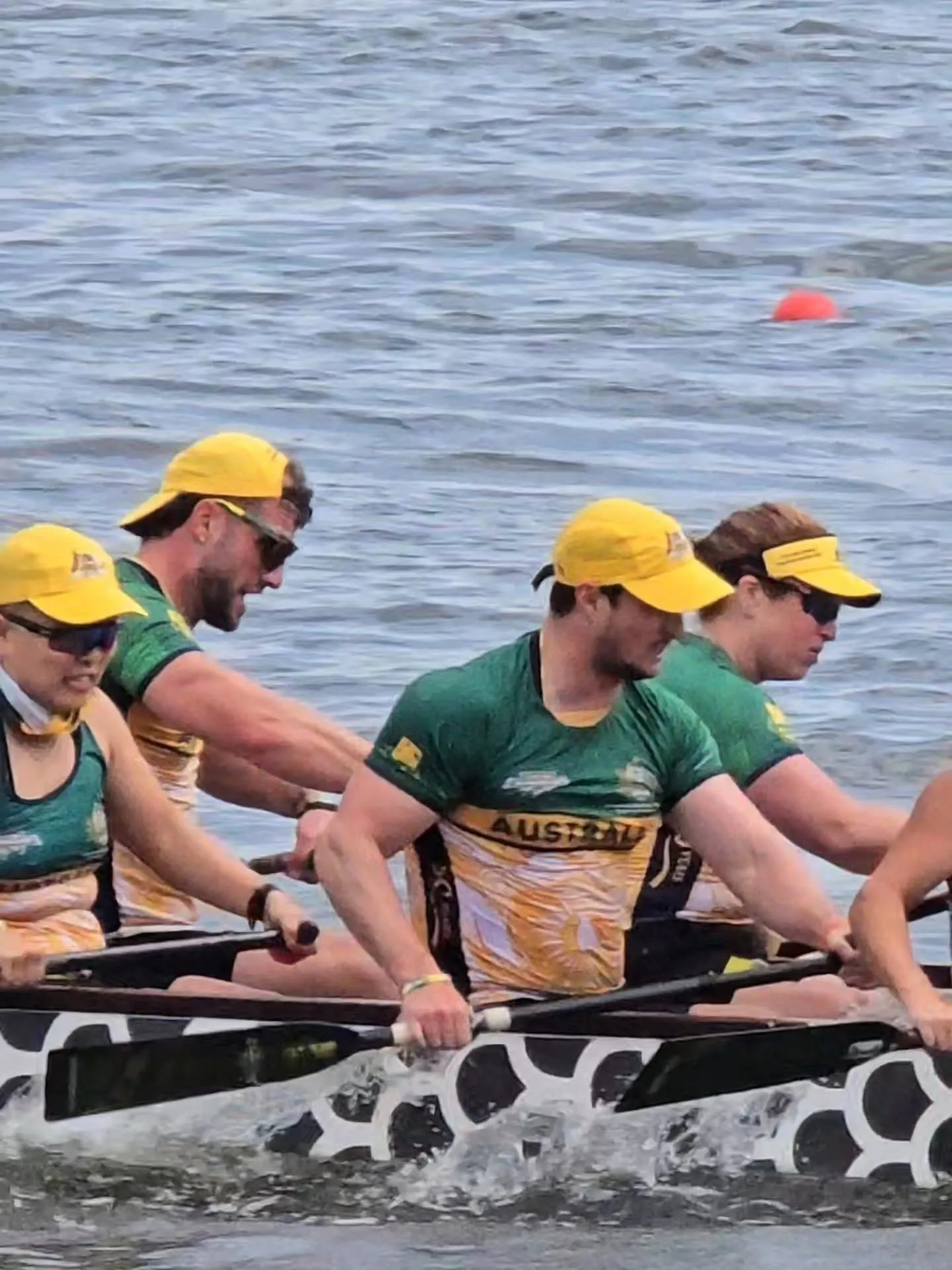 Paddlers in green and gold Australian team kit pulling hard