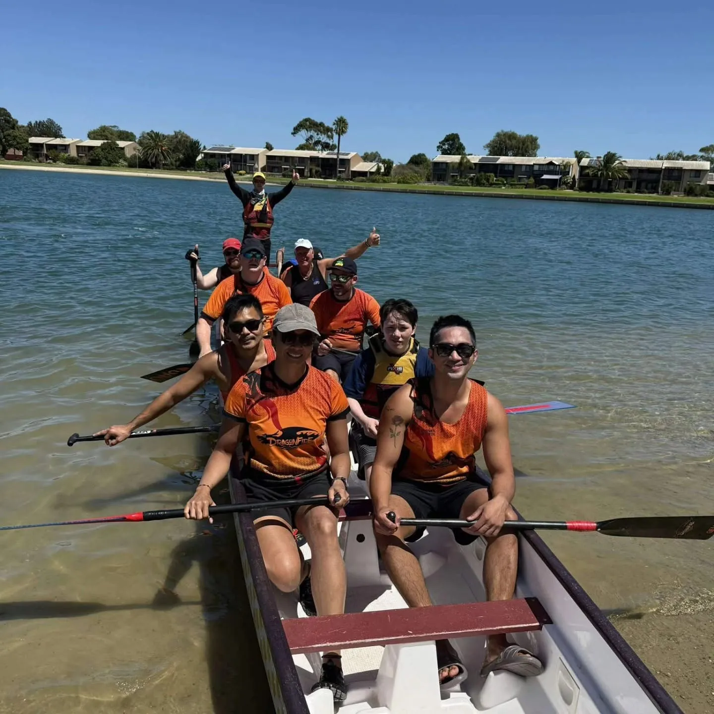 A crew cheering from the boat with paddles raised