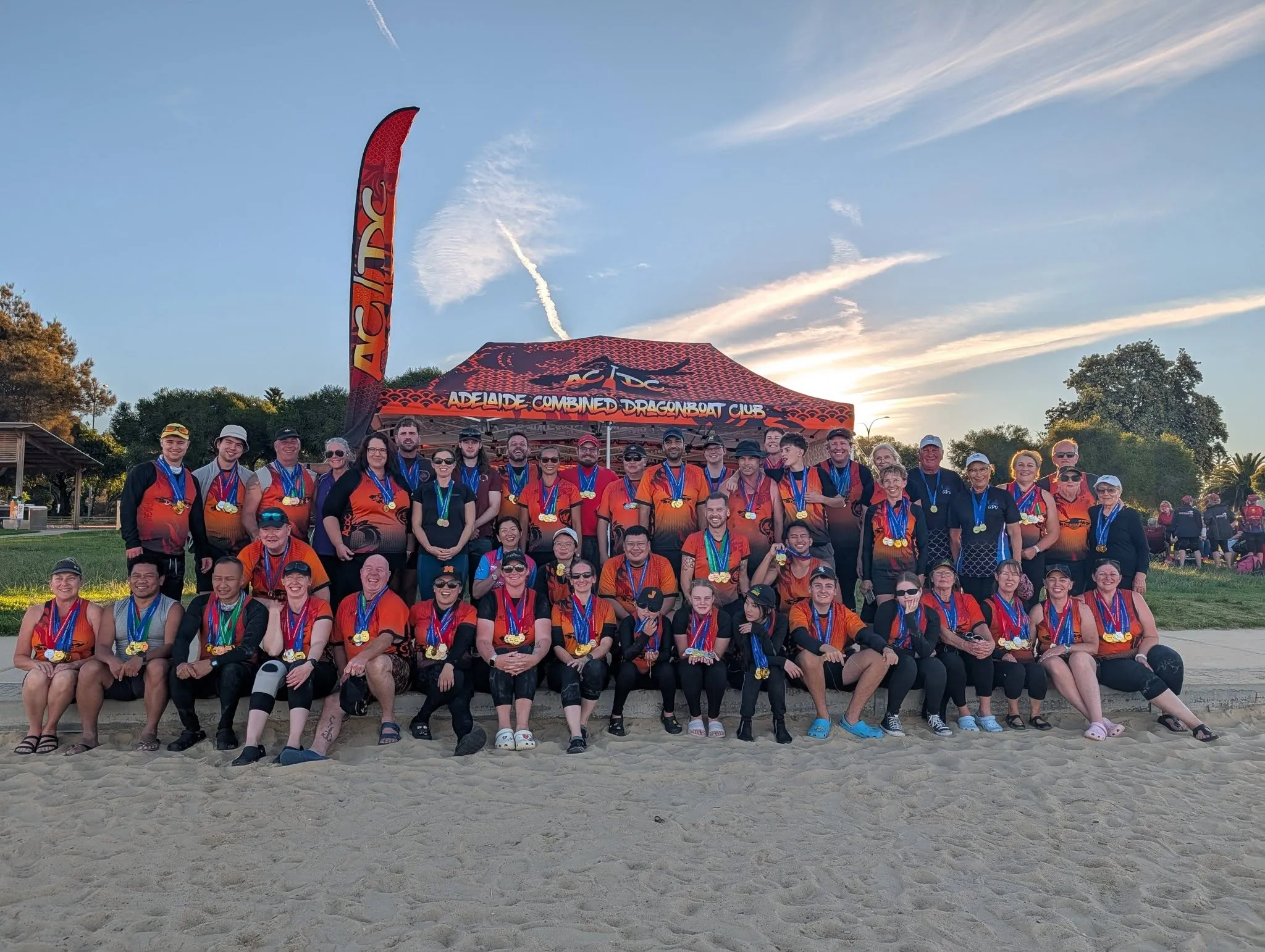 The ACDC club with their medals in front of the club marquee at sunset